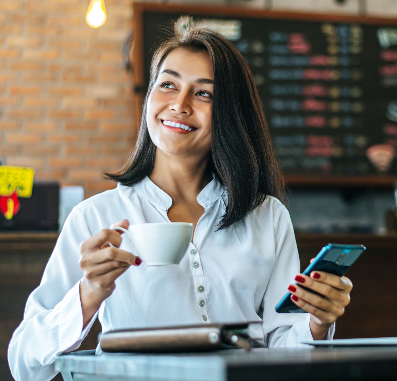 Empreendedora sorrindo enquanto organiza seu negócio pelo celular